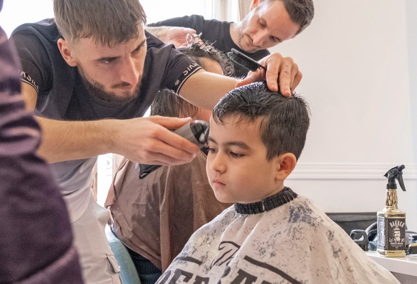 Volunteer hairdresser giving a haircut to a Ukranian refugee boy